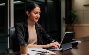 Frau sitz in einem Konferenzraum und arbeitet an einem Laptop