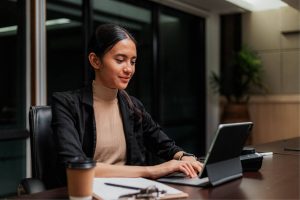Frau sitz in einem Konferenzraum und arbeitet an einem Laptop