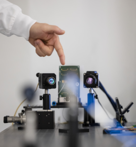 Förderung Forschung und Entwicklung: Ein experimentelles Setup mit zwei Kameras auf einem Tisch und eine Hand zeigt darauf
