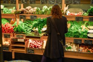 Nahversorgung in Österreich: Eine Frau steht vor einem Gemüseregal im Lebensmitteleinzelhandel
