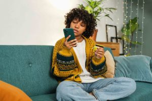 E-Commerce in Österreich 2026: eine Frau sitzt auf dem Sofa und shoppt mit ihrem Hady online.